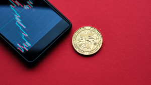 Tether cryptocurrency coin and a smartphone showing a trading chart